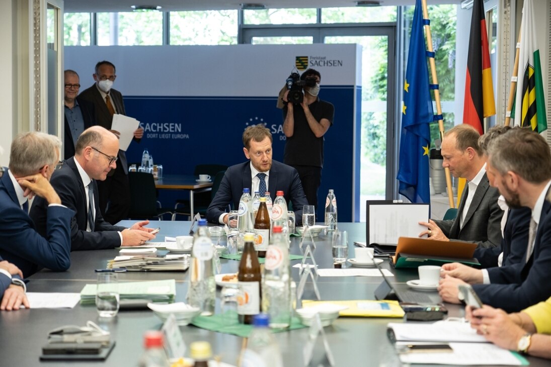 Frontaufnahmen des sächssichen MInisterpräsidenten sitzend an einem Tisch im Gespräch mit weiteren Kabinettsmitgliedern (rechts und links platziert)