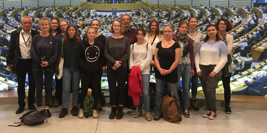 Abiturientinnen auf Gruppenbild mit Dr. Peter Jahr im Europäischen Parlament. Im Hintergrund ist der große Sitzungssaal zu sehen.