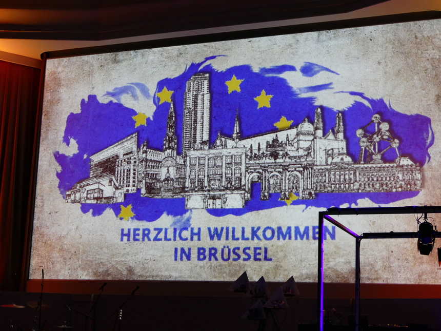 gezeichnete Skyline von Brüssel wird an die Wand projeziert, Raum ist abgedunkelt, auf dem Bild steht der Text Herzlichen willkommen in Brüssel
