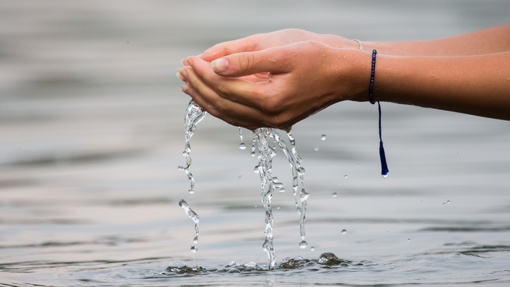 Eine Frau lässt Wasser durch ihre Hände laufen.