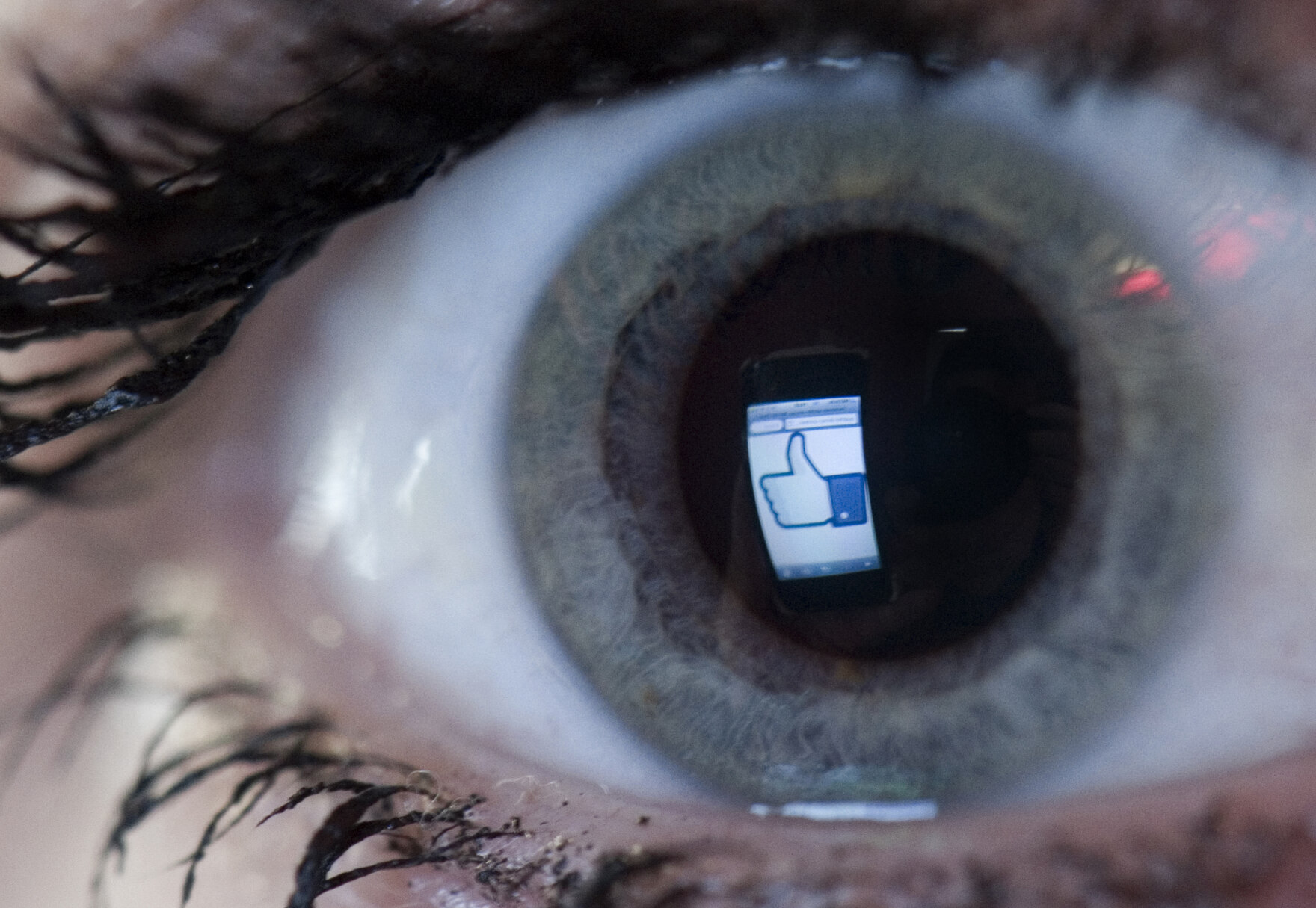 Großaufnahme eines Auges, in dem sich der Like-Button von facebook spiegelt.